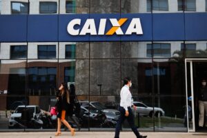Pessoas andando na rua em frente a caixa economica federal, como financiar um imóvel na caixa